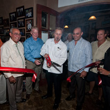 Shop owner Bill Niederer cuts the red ribbon as Pepin Garcia, left, and son Jaime, right, look on with others.